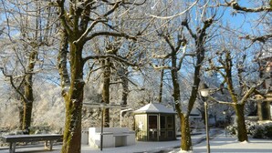 Un parque cubierto de nieve con un pabellón, bancos y un sendero.