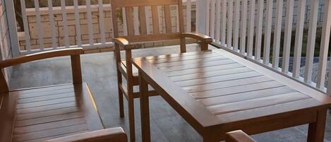 A wooden deck with a table and chairs, overlooking a landscape with a sunset.