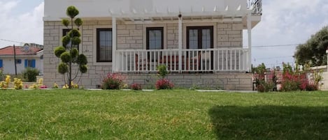 Una casa de dos pisos con fachada blanca, techo de tejas y un pequeño balcón.