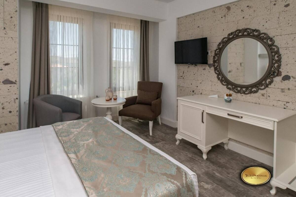 Une chambre d’hôtel équipée d’un lit, d’un bureau, d’une chaise, d’une télévision et d’un miroir.