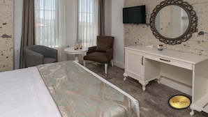 A hotel room with a bed, a desk, a chair, a television, and a mirror.