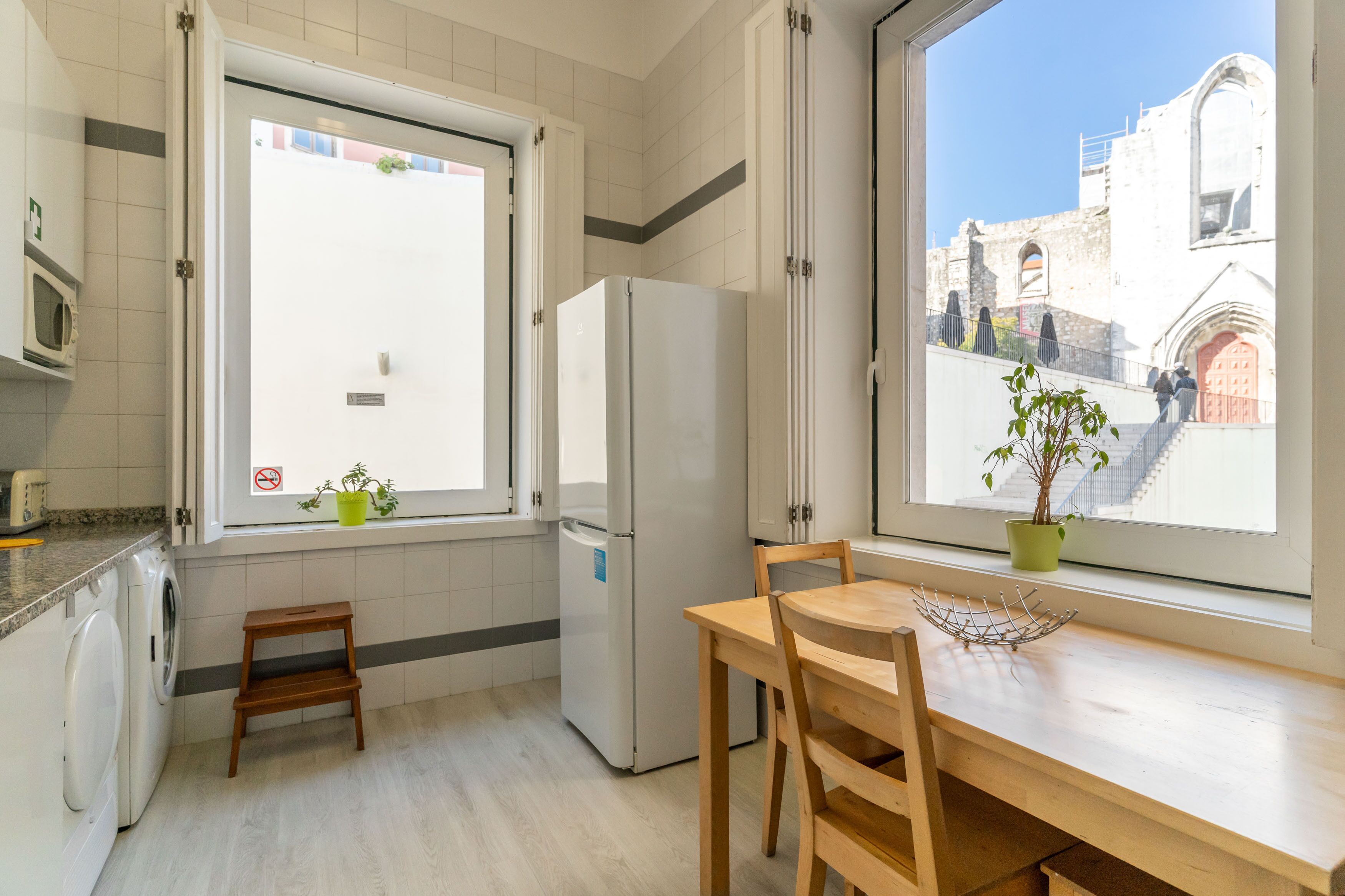 A kitchen with a dining table, a refrigerator, a microwave, and a washing machine.