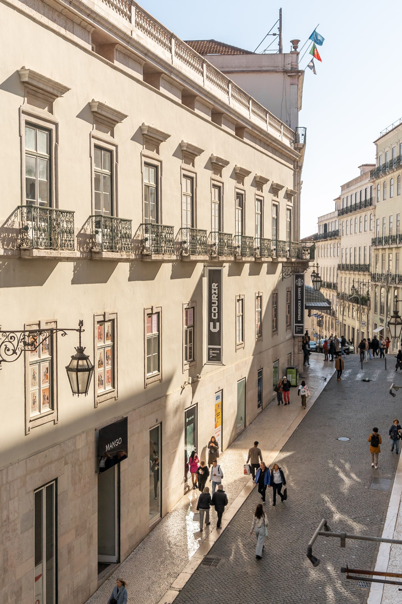 A historic building with a cobblestone street, large windows, and balconies.