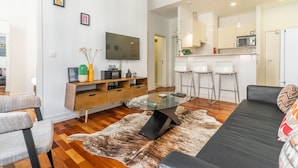 Una sala moderna con una mesa de centro de vidrio, un sofá y un comedor con taburetes de bar.