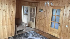 Un intérieur en bois avec un canapé, un tapis à motifs, une porte dotée de panneaux en verre dépoli et un ventilateur de plafond.