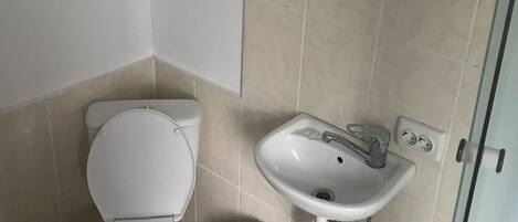 A bathroom with a toilet, sink, and trash bin.