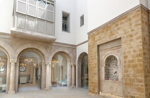 Une cour spacieuse agrémentée d’arcades, d’une fontaine et d’un espace aménagé pour s’asseoir.