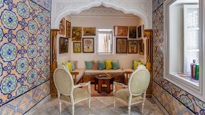 A room with a patterned tile wall, a sofa with cushions, a wooden table, and chairs. - Dar el Jeld Hôtel & Spa (Tunis)