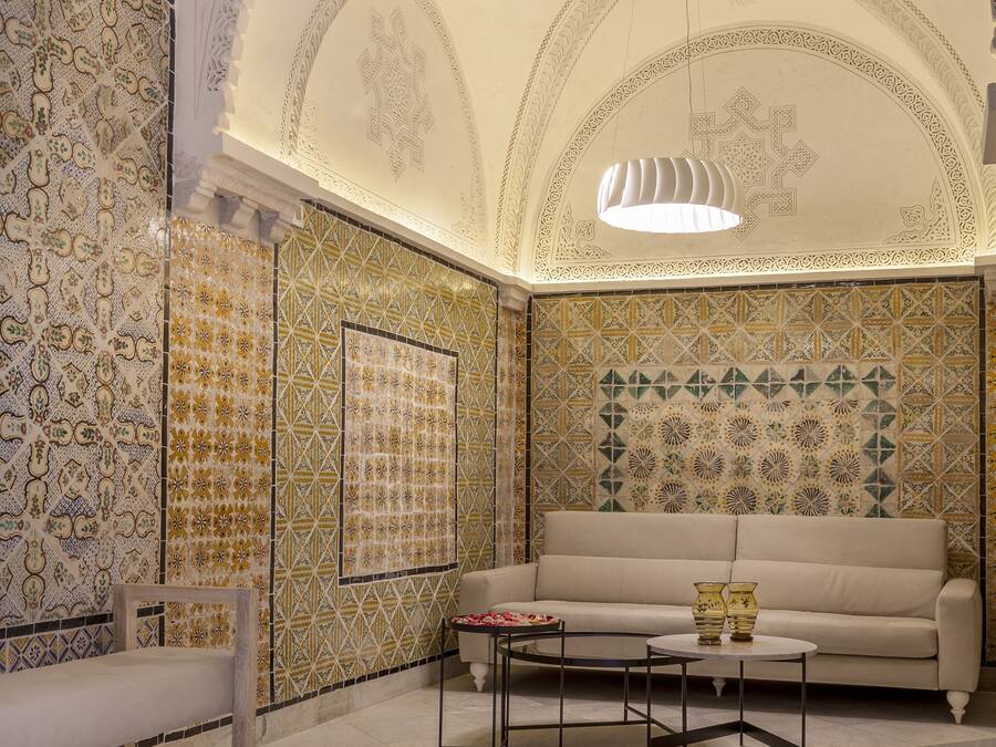 A room with a patterned wall, a sofa, a coffee table, and a bench.