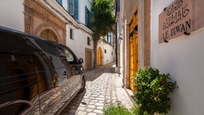 A narrow street with a parked car and a building with a sign reading "LE DIWAN". - Dar el Jeld Hôtel & Spa (Tunis)