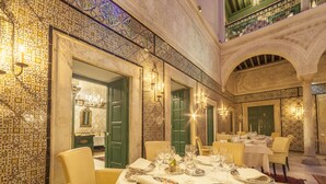 A luxurious dining area with ornate tile walls, green doors, and a high ceiling with intricate designs. Tables are set with fine china, silverware, and candles. - Dar el Jeld Hôtel & Spa (Tunis)