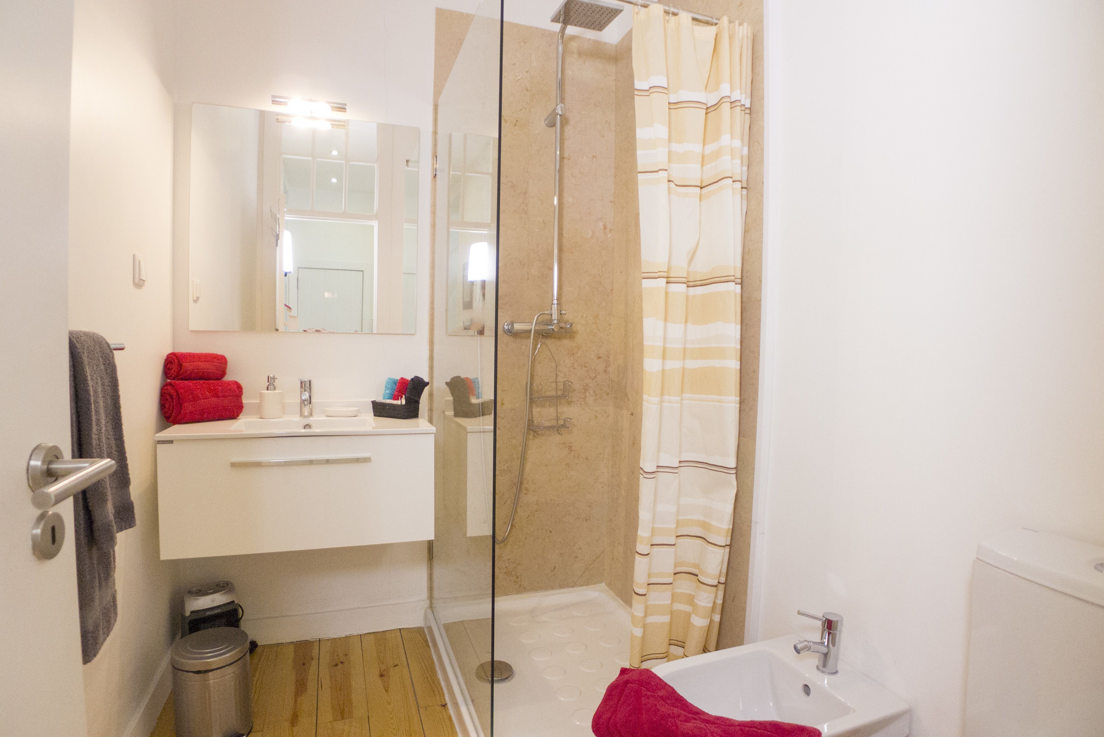 Un baño moderno con cabina de ducha de vidrio, lavamanos blanco y espejo sobre el lavamanos.