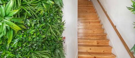 Una escalera de madera con un muro cubierto de plantas verdes a la izquierda.