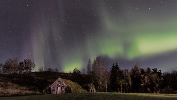 A rural landscape with a small house and a grassy field under a starry night sky. - Dalshöfði Guesthouse (Kirkjubæjarklaustur)