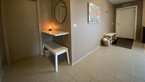 A hallway with a white bench, a small table with a lamp, a wall-mounted mirror, and a framed map. - Dalshöfði Guesthouse (Kirkjubæjarklaustur)
