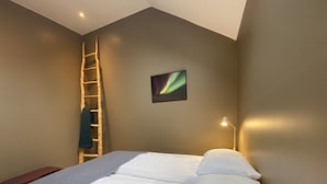 A bedroom with a bed, a ladder, a wall-mounted picture, and a desk lamp. - Dalshöfði Guesthouse (Kirkjubæjarklaustur)