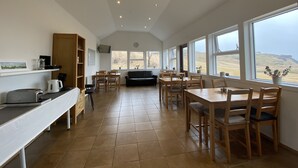 A spacious kitchen with a dining area, large windows, and a view of the countryside. - Dalshöfði Guesthouse (Kirkjubæjarklaustur)
