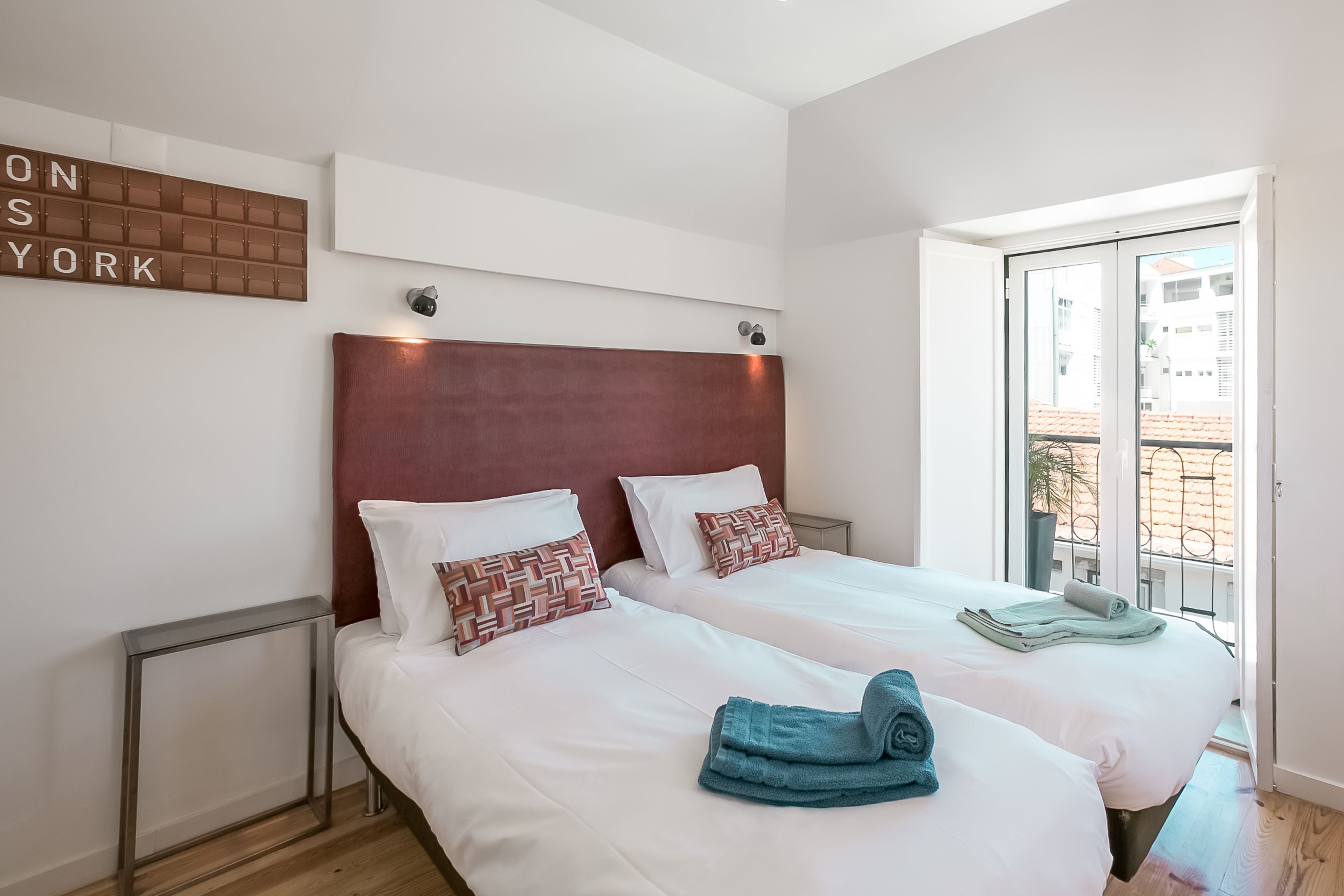 Una habitación de hotel con dos camas, un ventanal grande y un letrero en la pared.