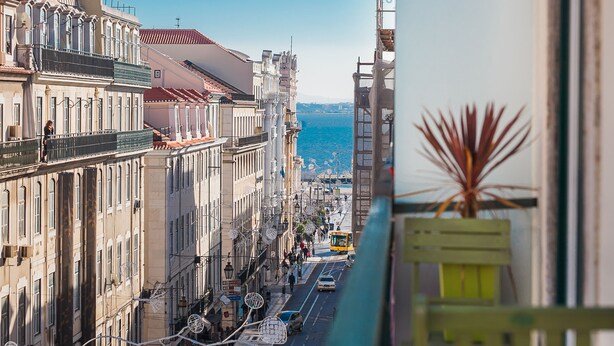 Une vue de rue avec des bâtiments, un autobus et une vue dégagée sur la mer.