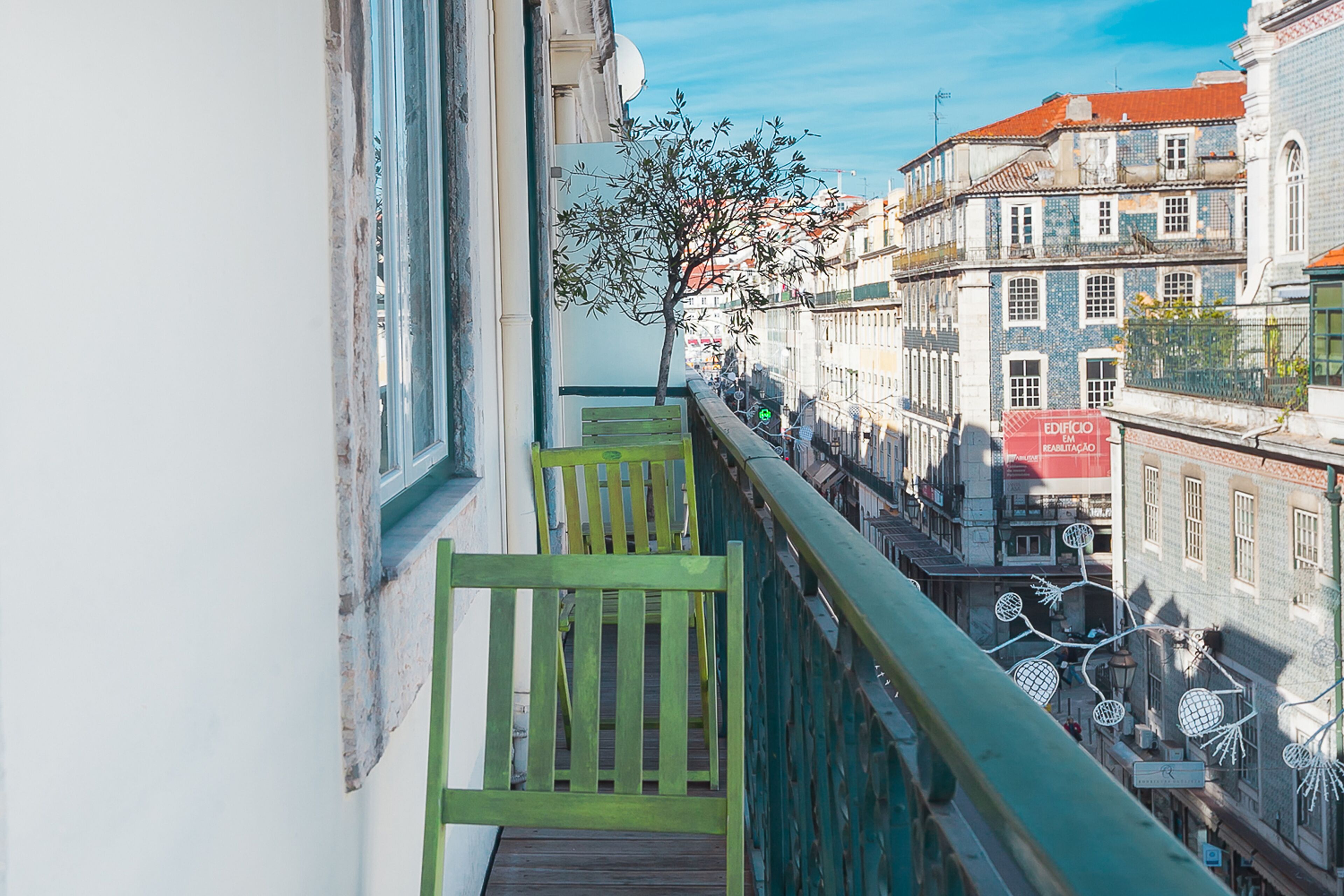 A balcony with a view of a tree and buildings.