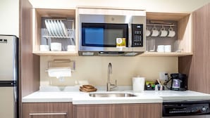 A compact kitchen with a stainless steel microwave, a coffee maker, and a dishwasher. - Home2 Suites by Hilton Oklahoma City NW Expressway (Oklahoma City)