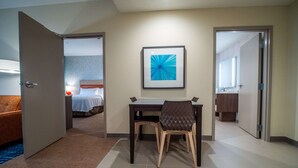A hotel room with a bed, a desk with a chair, a framed picture on the wall, and a bathroom visible through an open door. - Home2 Suites by Hilton Oklahoma City NW Expressway (Oklahoma City)