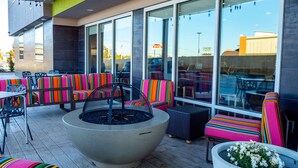 An outdoor seating area with colorful striped chairs and a large fire pit. - Home2 Suites by Hilton Oklahoma City NW Expressway (Oklahoma City)