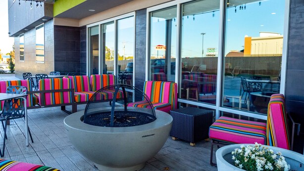 An outdoor seating area with colorful striped chairs and a large fire pit. - Home2 Suites by Hilton Oklahoma City NW Expressway (Oklahoma City)