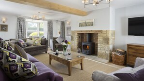 A cozy living room with a fireplace, a sofa set, a coffee table, and a television mounted on the wall.