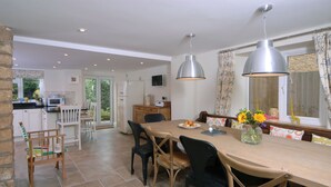 A spacious kitchen with a dining area, a refrigerator, a microwave, and a large window with curtains.