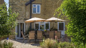 An outdoor patio with two umbrellas, a table, and chairs.