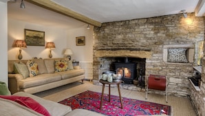 Un salon chaleureux avec une cheminée en pierre, un canapé, une table basse et un tapis à motifs.