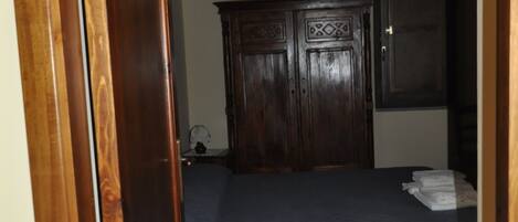 Una habitación con una cama, un armario de madera y suelo de baldosas.