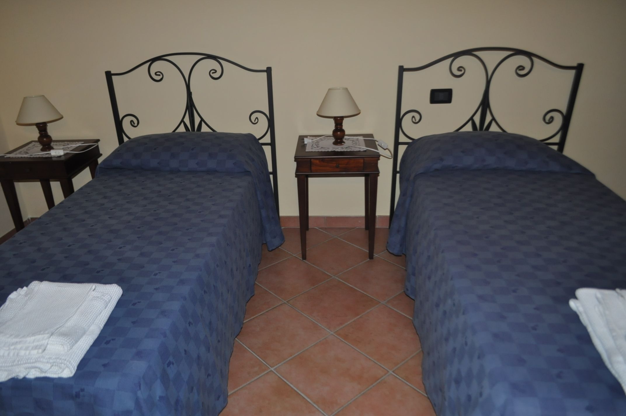 Una habitación con dos camas, cada una con cabecera y piecera a juego, y una mesita entre ellas.