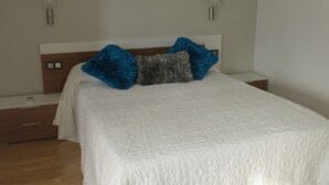 Un dormitorio con una cama grande, un cabecero de madera y una mesita de noche.