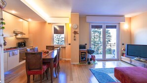 A modern kitchen with a dining area, a TV, and a large window. - Dimora Gu - lake view terrace, 100m from the beach (Bardolino)