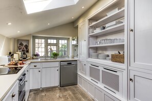 A kitchen with white cabinetry, a dishwasher, and a window with a view of greenery.