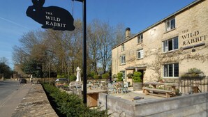 A building named 'The Wild Rabbit' with outdoor seating and a stone facade.