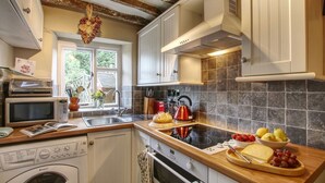 A modern kitchen with a dishwasher, microwave, and oven. There is a window with a view of greenery outside.