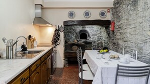 Een keuken met een oven in een stenen muur, een spoelbak en een eettafel gedekt voor twee personen.