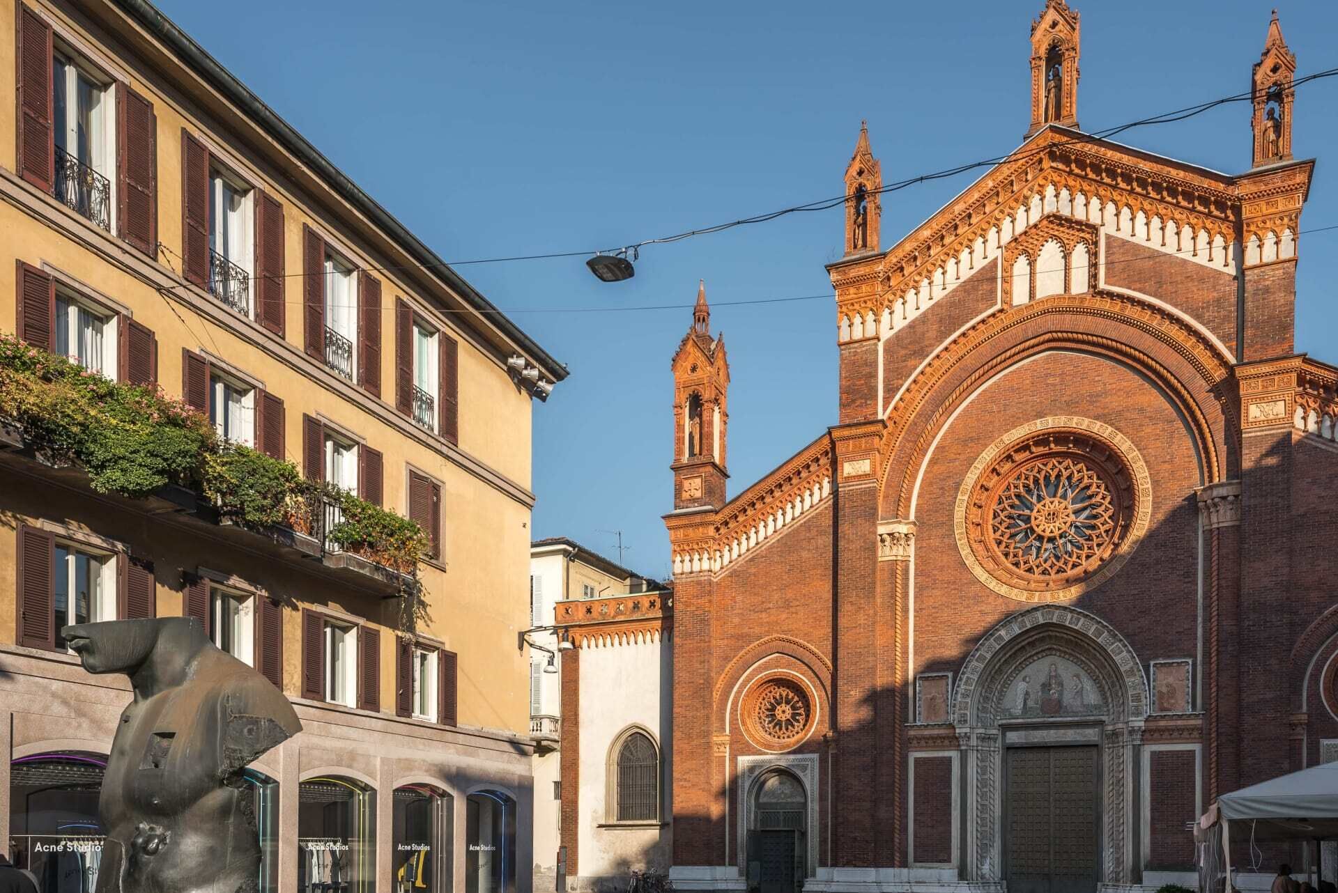 A street view with a prominent church featuring a large circular window and a bell tower.