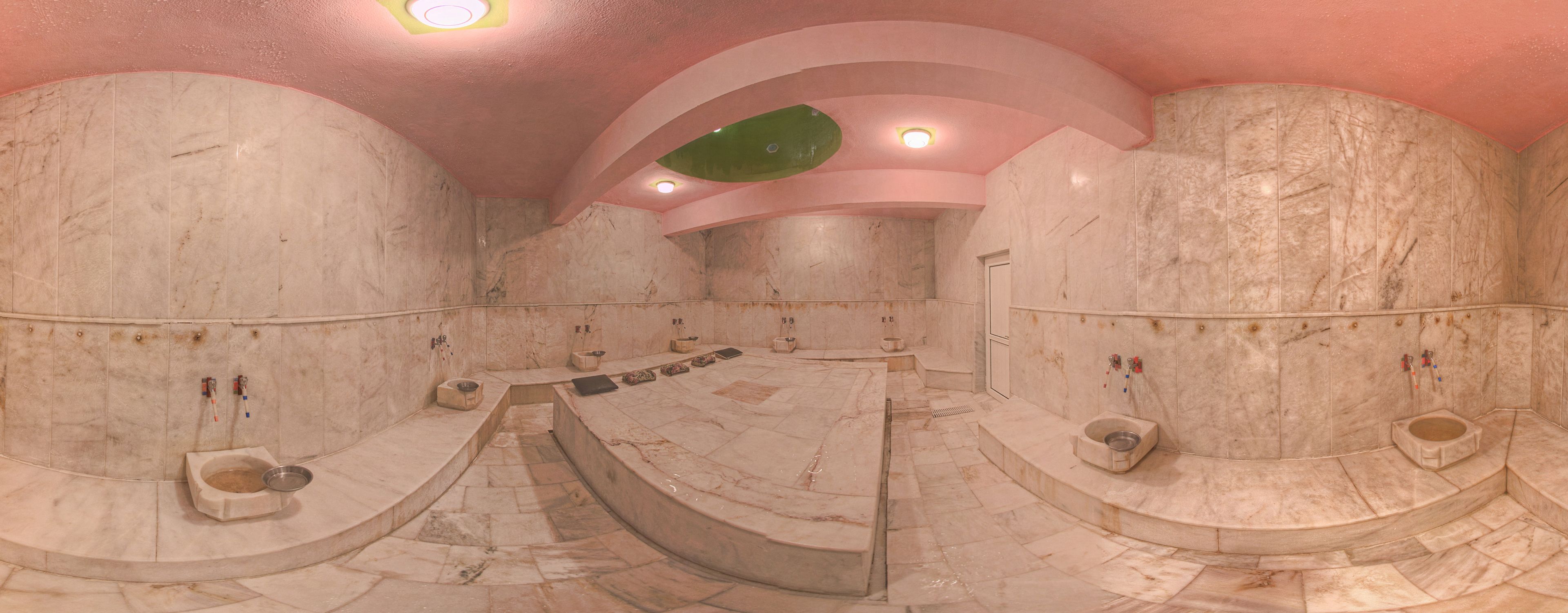 A luxurious bathroom with marble walls, multiple sinks, and a central seating area.