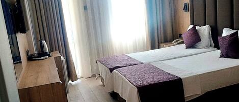 A hotel room with a bed, bedside tables, a desk, and a chair.