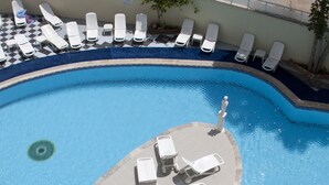 A pool with lounge chairs arranged in a semi-circle, a checkered floor, and a clear blue pool. - Meryemana Hotel (Didim)