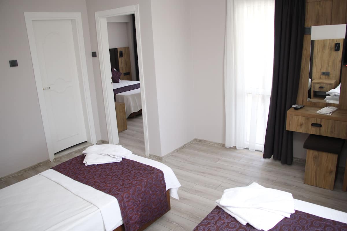 A hotel room with two beds, a wooden desk, a mirror, and a bathroom visible through an open door.