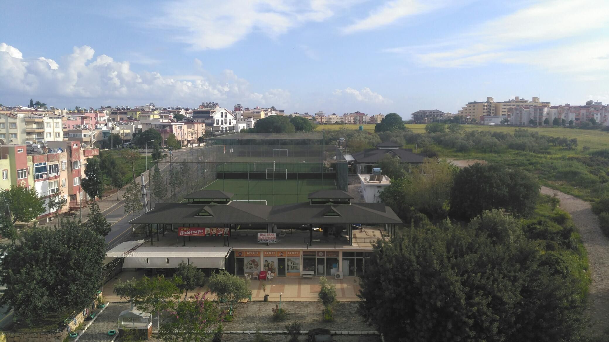 Uma instalação esportiva com gramado verde, áreas de assentos cobertas e um edifício com várias entradas.