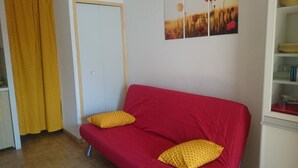 A room with a red sofa, two yellow pillows, a white door, and a yellow curtain. - Studio 15 minutes from the Pont de Gau ornithological park (Saintes-Maries-De-La-Mer)