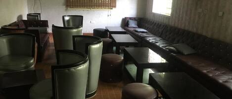 Un salon moderne avec un canapé en cuir, plusieurs fauteuils et des tables.