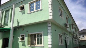 Ein zweistöckiges Gebäude mit grüner Fassade, weißen Verzierungen und zahlreichen Fenstern.