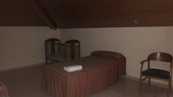 Una habitación pequeña y con poca luz, con una cama individual, una silla y techo de madera.